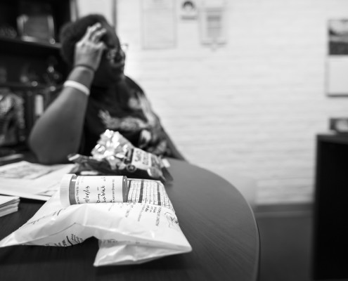 A homeless lady is given medication for water retention in her ankles due to having to sleep sitting up in a metal chair. The center uses chairs instead of cots to maximize their capacity.