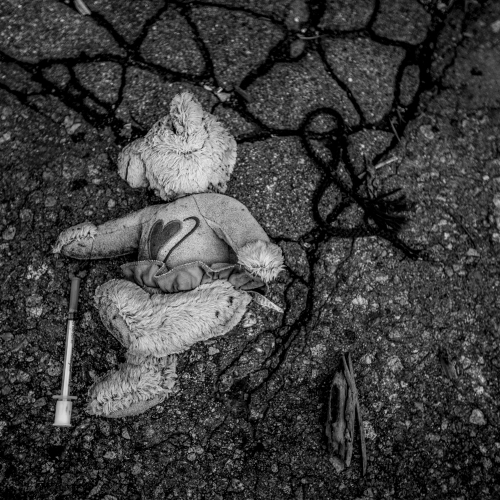 An abandoned stuffed bear is found beside a used syringe amongst the rubble of the dilapidated Packard Plant.